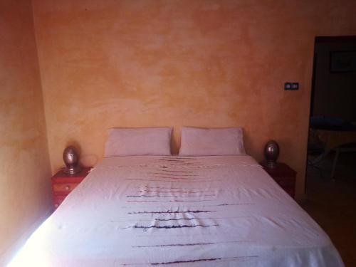 ein Schlafzimmer mit einem Bett mit weißer Bettwäsche und zwei Nachttischen in der Unterkunft Moha House in Merzouga