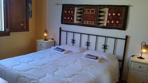 a bedroom with a white bed with two books on it at Appartamenti Le Cicale in Fertilia