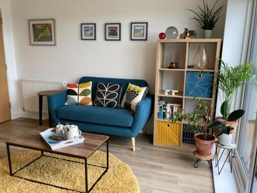a living room with a blue couch and a table at Dog Friendly Stylish Modern Flat, near Beach in Newquay