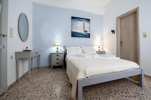 a white bedroom with a bed and a mirror at Giasemi Room No 7 Irakleia in Livadi Astypalaias
