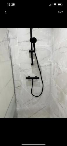 a shower nozzle in a white tiled bathroom at Appartement centre ville in LʼAigle