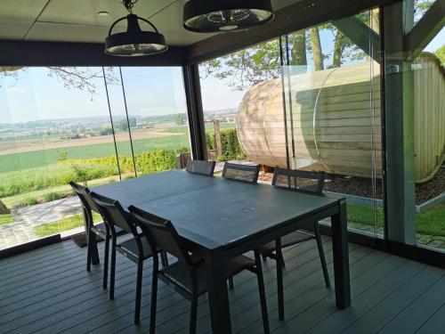 a dining room with a table and chairs and a large window at KoppenHerberg in Oudenaarde