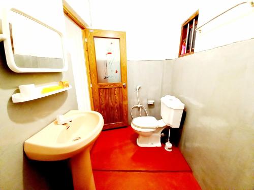 uma casa de banho com um WC branco e um lavatório. em Coco Garden Villas em Hikkaduwa