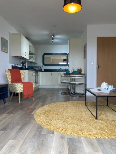 cocina y sala de estar con mesa y alfombra en Dog Friendly Stylish Modern Flat, near Beach, en Newquay