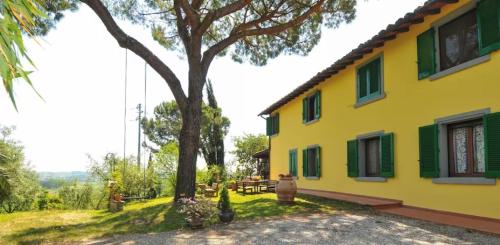 een geel huis met groene luiken en een boom bij Agriturismo La Pineta in Fucecchio