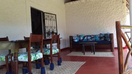 ein Wohnzimmer mit einem Sofa, einem Tisch und Stühlen in der Unterkunft Les Datchi Cottages in Diani Beach