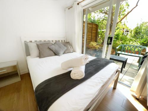 um quarto com uma cama e uma grande janela em Luxurious House near Excel- Air Conditioning, 9 Beds, 2 Baths, Garden, fast WiFi em Londres