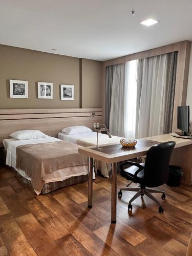 1 dormitorio con 2 camas, escritorio y TV en APART HOTEL SENSE II - Localizado em Hotel, en Manaus