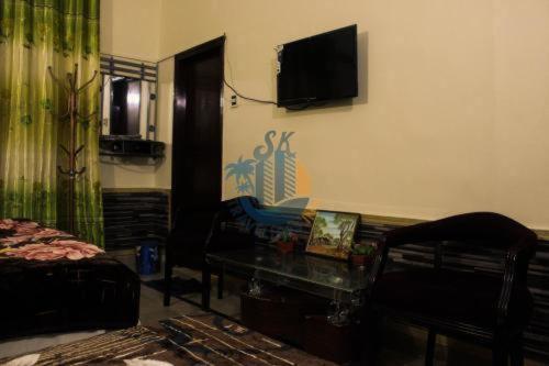 een woonkamer met een bank en een tv aan de muur bij Sk Travellers Inn in Karachi