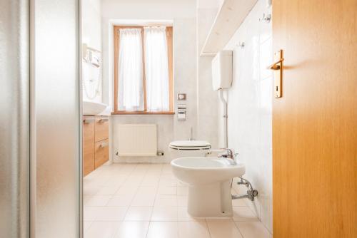 a white bathroom with a toilet and a sink at CROSINA HOLIDAY - Casa Lucia in Ledro