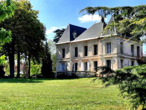 une grande maison blanche sur une pelouse dans l'établissement Chateau Tanesse de Tourny, à Bayon