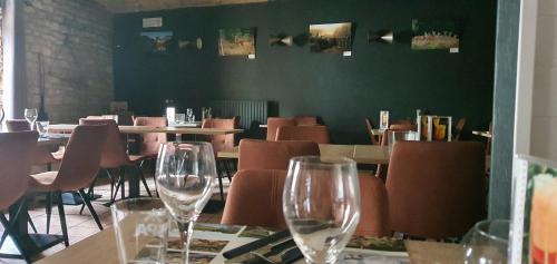 a restaurant with chairs and wine glasses on a table at La Vieille Ferme Chassepierre in Chassepierre