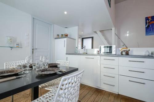 une cuisine avec des armoires blanches et une table et des chaises dans l'établissement Cottage Le Rêve d'Esther, atypical and elegant!, à Cholet