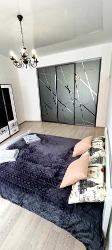 a bedroom with a large bed and a chandelier at Центр Апарт in Ternopilʼ