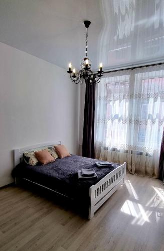 1 dormitorio con cama y lámpara de araña en Центр Апарт, en Ternopilʼ