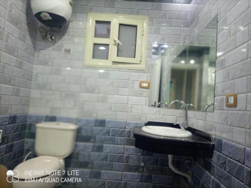 ein Badezimmer mit einem WC, einem Waschbecken und einem Spiegel in der Unterkunft ستانلي اسكندريه in Alexandria