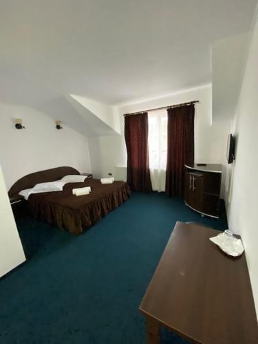 Habitación de hotel con 2 camas y mesa en Pensiunea COCO en Năsăud