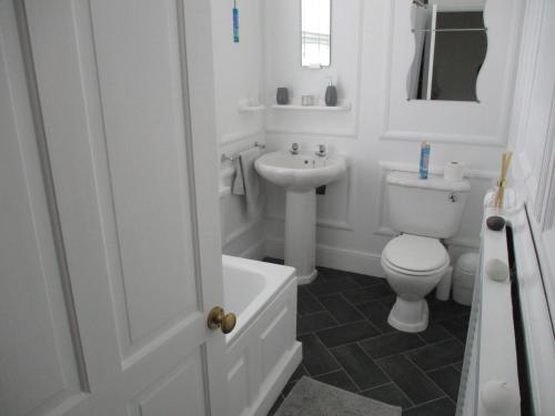 a white bathroom with a toilet and a sink at Lovely Spacious 3 Bedded First Floor Apartment in Ryde