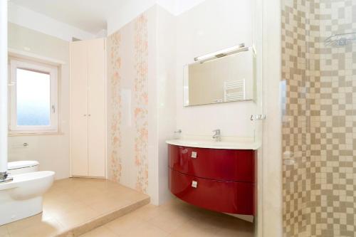 uma casa de banho com um lavatório vermelho e um WC. em Guest House Emily Suites Sorrento em Sorrento