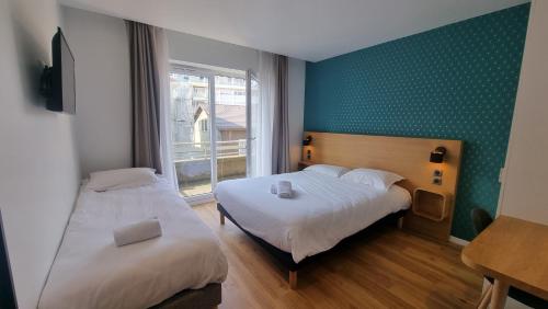 2 Betten in einem Zimmer mit grünen Wänden und einem Fenster in der Unterkunft Oskar Hotel in Annemasse
