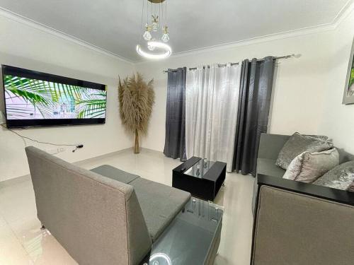 a living room with a couch and a flat screen tv at Apartamento Cómodo & Seguro in Santo Domingo