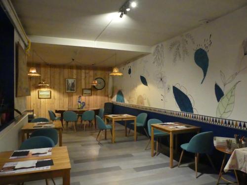 a restaurant with tables and chairs and a wall with flowers at Le 9 en Cuisine in Rabastens