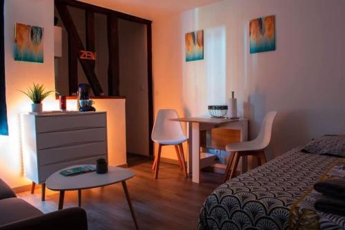 une chambre avec un lit, une table et des chaises dans l'établissement Studio Charmant Confortable TV Centre Ville Louviers, à Louviers