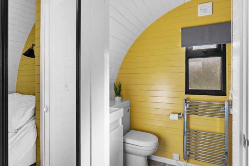 baño con aseo y pared amarilla en Honeycrisp, Apple Tree Glamping, Nr Wells, en Wells