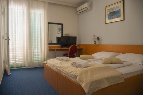 1 Schlafzimmer mit 2 Betten und einem Schreibtisch mit einem Computer in der Unterkunft Hotel Sirena Hvar in Hvar