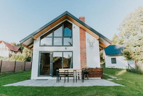 una casa con una mesa y sillas en el patio en Nowe Domki Jeleni Szlak, en Ustrzyki Dolne