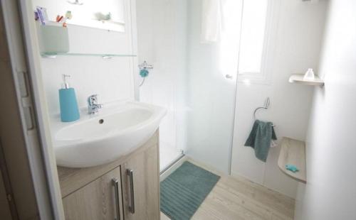 a white bathroom with a sink and a shower at Grand mobil home tout confort ES 93 in Fréjus