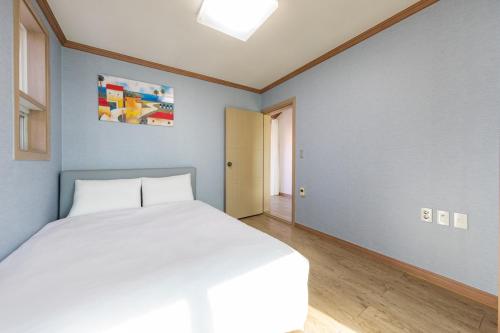a bedroom with a white bed and a blue wall at Clear morning pet friendly pension in Gyeongju