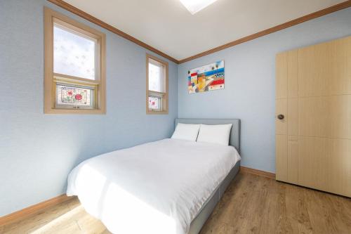a bedroom with a white bed and two windows at Clear morning pet friendly pension in Gyeongju