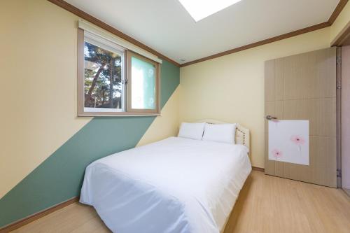 a bedroom with a white bed and a window at Clear morning pet friendly pension in Gyeongju