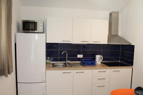 a kitchen with white cabinets and a white refrigerator at Gorgonia Apartments in Verunić