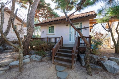 a small house with a wooden staircase in front of it at Clear morning pet friendly pension in Gyeongju
