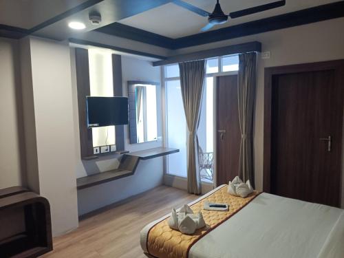 a bedroom with a bed with a tv and a window at Golden Peaks Hotel & Restaurant in Kalimpong
