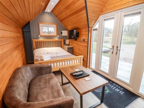 Habitación con cama, silla y mesa. en Willow Lodge At Bridge Lake Farm & Fishery, en Banbury