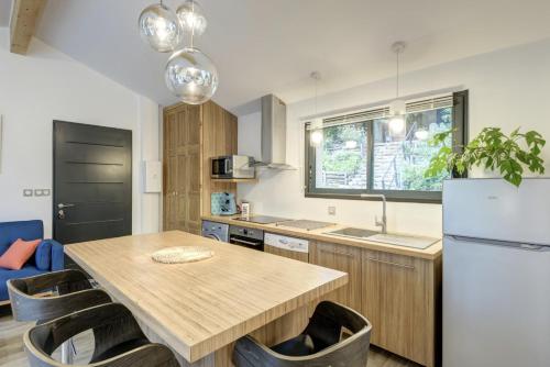 une cuisine avec une table en bois et un réfrigérateur dans l'établissement PAUSE NATURE Maison Cosmos avec parking gratuit, à Lapeyrouse-Fossat
