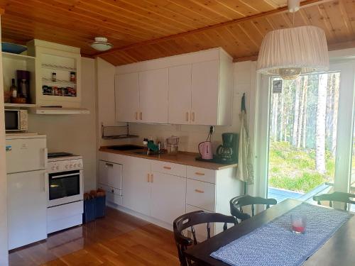 a kitchen with white cabinets and a table with chairs at Sala Cabin in Sala