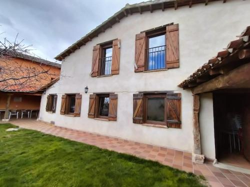 a house with wooden windows and a yard at Albergue Don Camino in Villalcázar de Sirga