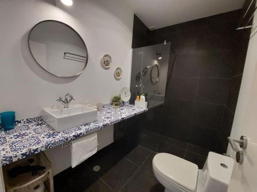ein Badezimmer mit einem Waschbecken, einem WC und einem Spiegel in der Unterkunft Apartment with Private Garden - Central Location in Lissabon