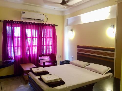 a bedroom with a large bed with pink curtains at Hotel Sun Rock in Kanyakumari