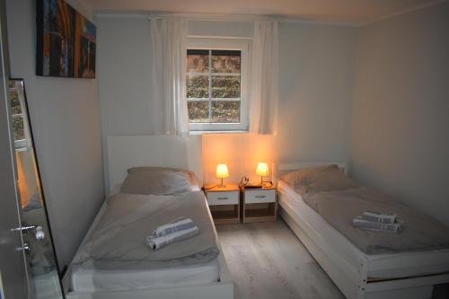 twee bedden in een kamer met een raam en twee lampen bij Ferienwohnung JaRa 1 in Stolberg