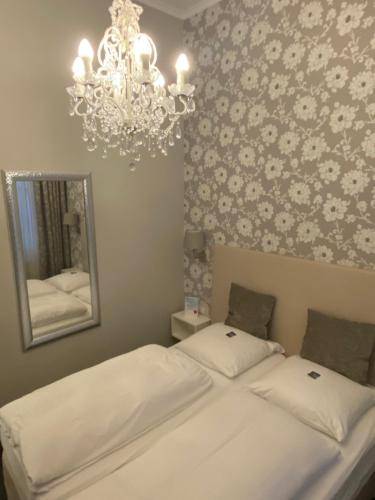 a bedroom with a bed with a mirror and a chandelier at Arthotel ANA Residence Bremen in Bremen