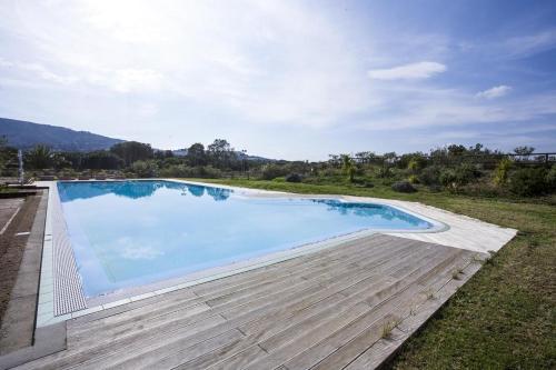 a large swimming pool in a field with a wooden deck at Appartamenti Verde Blu in Capoliveri