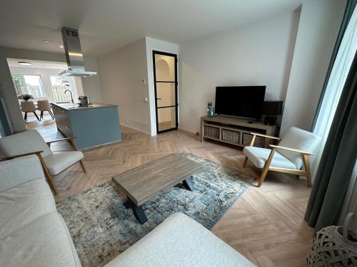 a living room with a couch and a table and a tv at Casa de Schans - 6 persoons vakantiehuis in Landgraaf