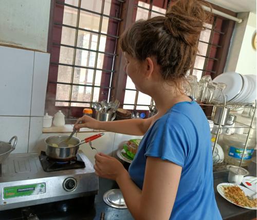 a woman stirring a pot on a stove in a kitchen at Angels' homestay Marari in Mararikulam