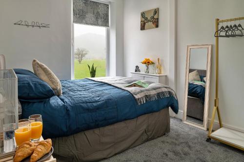 - une chambre avec un lit doté d'une couette bleue et d'une fenêtre dans l'établissement Finest Retreats - Smithfields, à Llanrwst