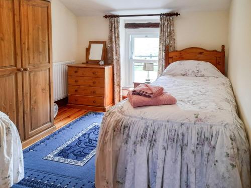 a bedroom with a bed and a dresser and a window at Greenrigg Cottage in Caldbeck